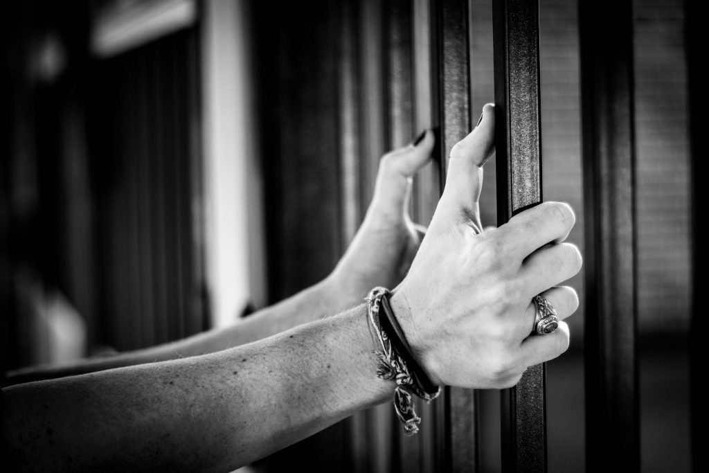 Hands handcuffed holding bars